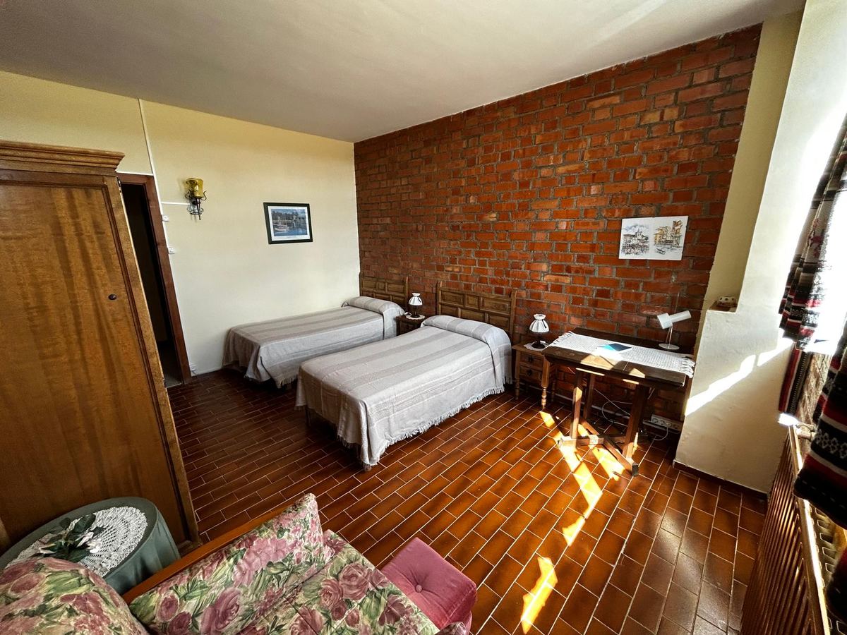 Habitación luminosa con dos camas y escritorio
